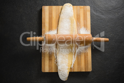 Overhead view of rolling pin on dough over cutting board