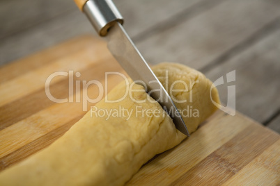 Cropped image of knife cutting dough