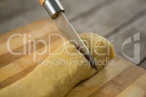 Cropped image of knife cutting dough