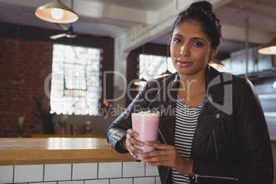 Portrait of woman holding milkshake glass in cafe
