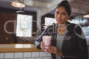 Portrait of woman holding milkshake glass in cafe
