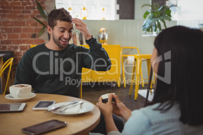 Woman giving ring to boyfriend at cafe