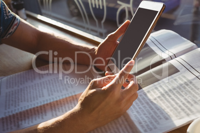 Cropped hands of man with newspaper holding tablet in cafe