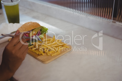 Cropped hand of woman having French fries in cafe