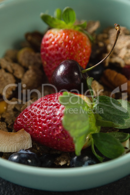 Bowl of breakfast cereals with fruits on black background