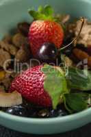 Bowl of breakfast cereals with fruits on black background