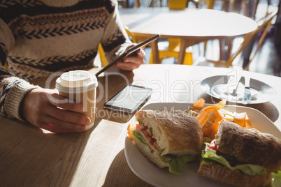 Mid section of man with breakfast using tablet in cafe