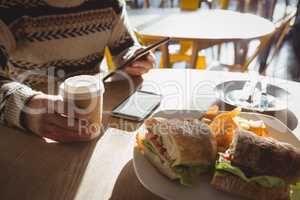 Mid section of man with breakfast using tablet in cafe