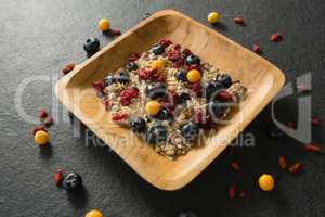 Plate of breakfast cereal with fruits on black background