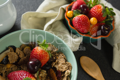 Bowl of breakfast cereals, fruits with spoon and napkin