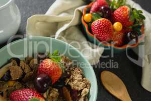 Bowl of breakfast cereals, fruits with spoon and napkin