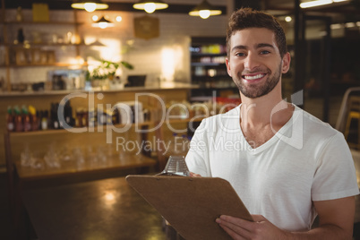 Portrait of waiter with clipboard at cafe