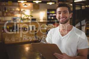 Portrait of waiter with clipboard at cafe