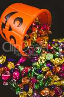 Orange bucket with chocolates over black background