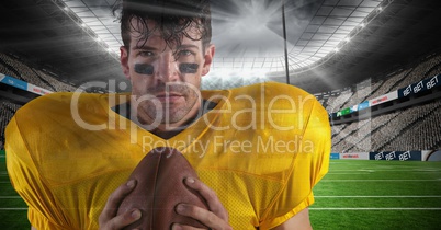 american football  player standing in stadium holding the ball