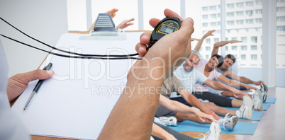 Composite image of cropped image of trainer holding stopwatch and clipboard