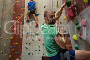Portrait of athlete climbing wall in health club