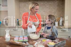 Mother and daughter preparing cup cake in kitchen