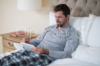 Man using digital tablet in bed