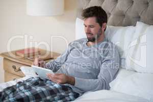 Man using digital tablet in bed