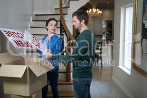 Couple opening cardboard boxes in living room