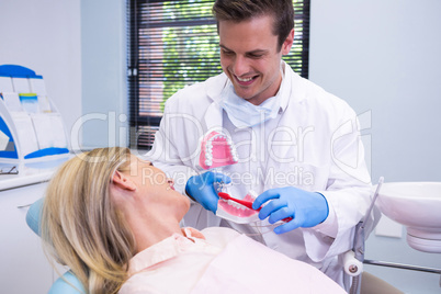 Dentist holding dental mould by woman at clinic