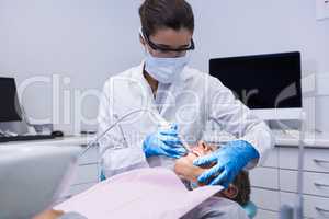 Dentist holding equipment while giving treatment to man