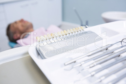Close-up of medical equipment  on table against man lying on dentist chair