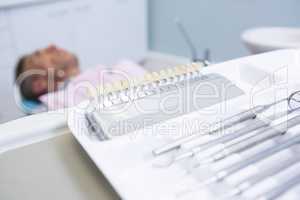 Close-up of medical equipment  on table against man lying on dentist chair