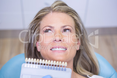 Extreme close up doctor holding tooth whitening equipment by smiling patient