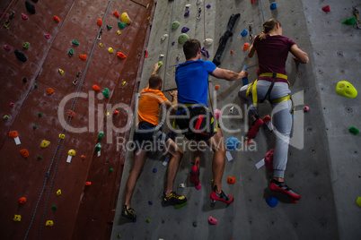 Low angle view of athletes and trainer climbing wall in gym