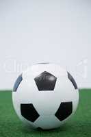 Football kept on artificial grass against white background