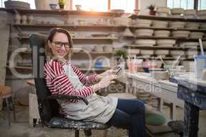 Portrait of female potter using digital tablet