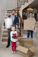 Parents and daughter opening cardboard boxes in living room