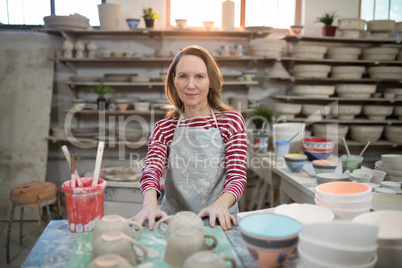 Portrait of female potter standing at worktop