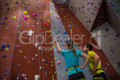 Athletes interacting while standing by climbing wall in gym