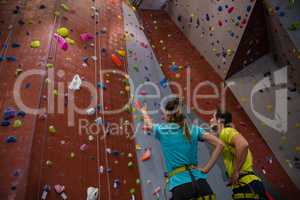 Athletes interacting while standing by climbing wall in gym