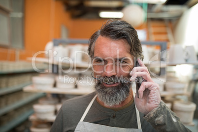 Male potter talking on mobile phone