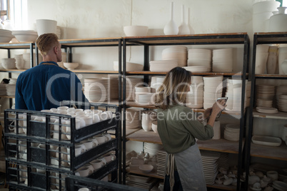 Male and female potter working maintaining records of earthenware