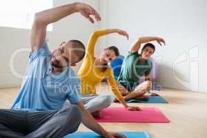 Yoga instructor with students exercising at club