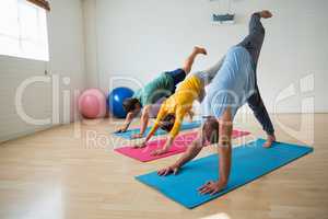 Instructor with students practicing downward facing dog pose with feet up