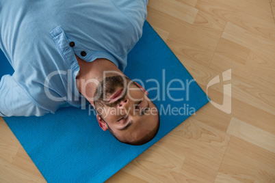 Yoga instructor exercising while lying on mat in yoga studio