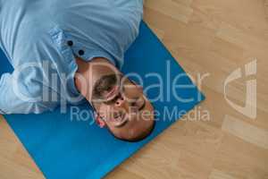 Yoga instructor exercising while lying on mat in yoga studio