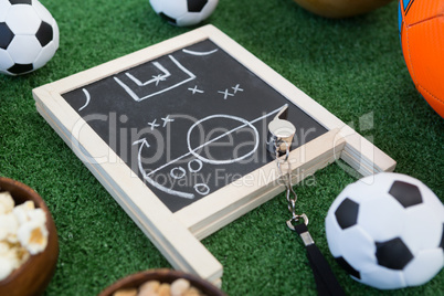 Strategy board, whistle and football on artificial grass