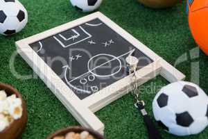 Strategy board, whistle and football on artificial grass