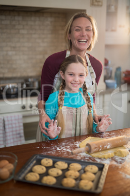 Happy mother and daughter having fun while preparing cookies in kitchen