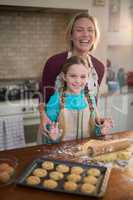 Happy mother and daughter having fun while preparing cookies in kitchen
