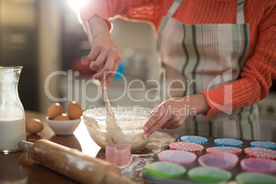 Woman mixing eggs and wheat flour in a bowl