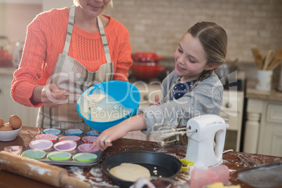 Mother and daughter preparing cup cake in kitchen