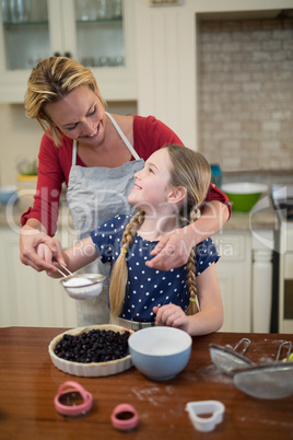 Mother and daughter preparing blue berry pie